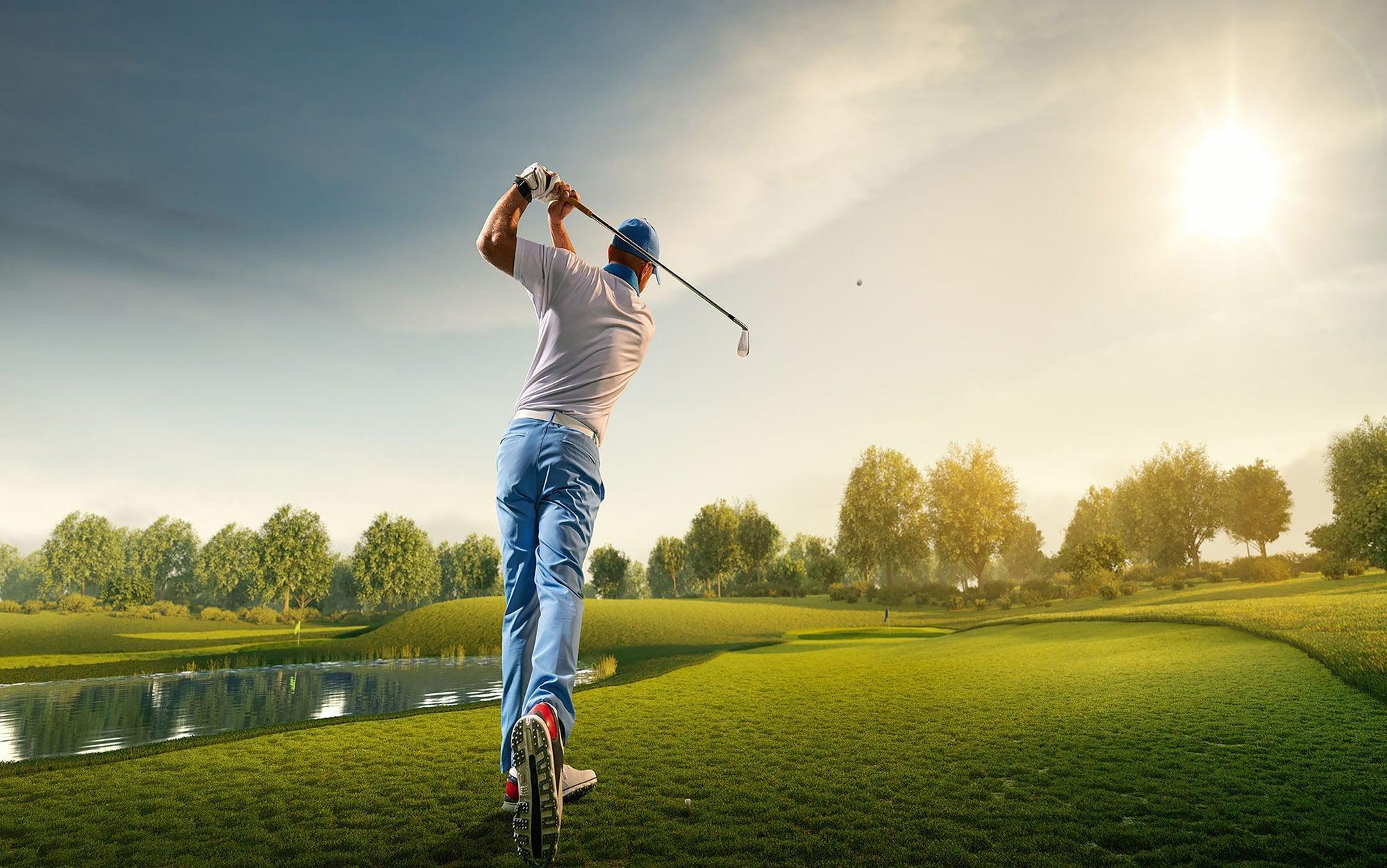 Golfer in action swinging a club on a sunny golf course with a clear sky