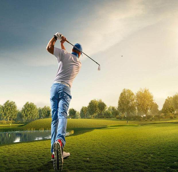 Golfer in action swinging a club on a sunny golf course with a clear sky