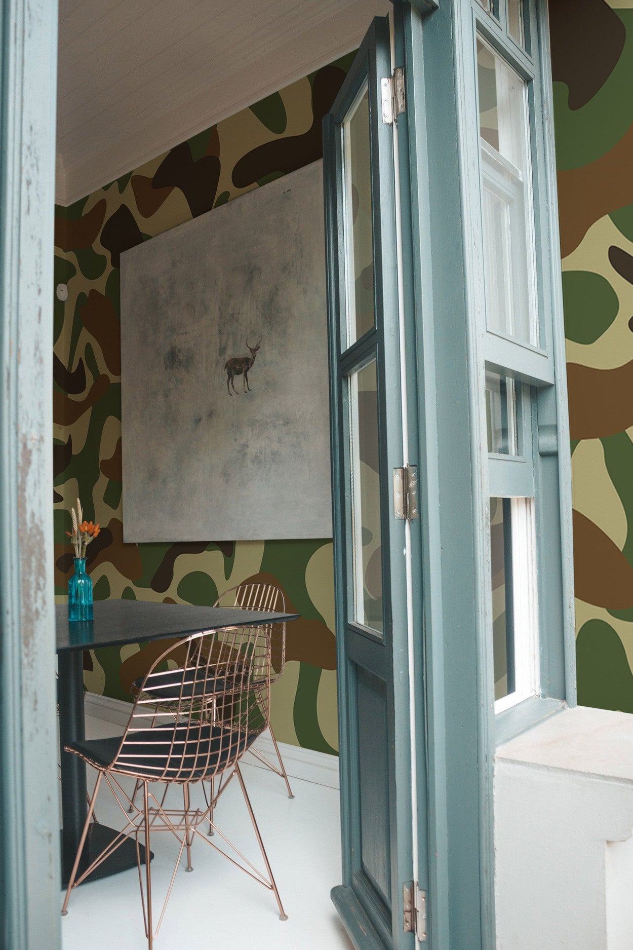 Interior view of a room with a large camouflage pattern wall mural, abstract art on the wall, and modern furniture.