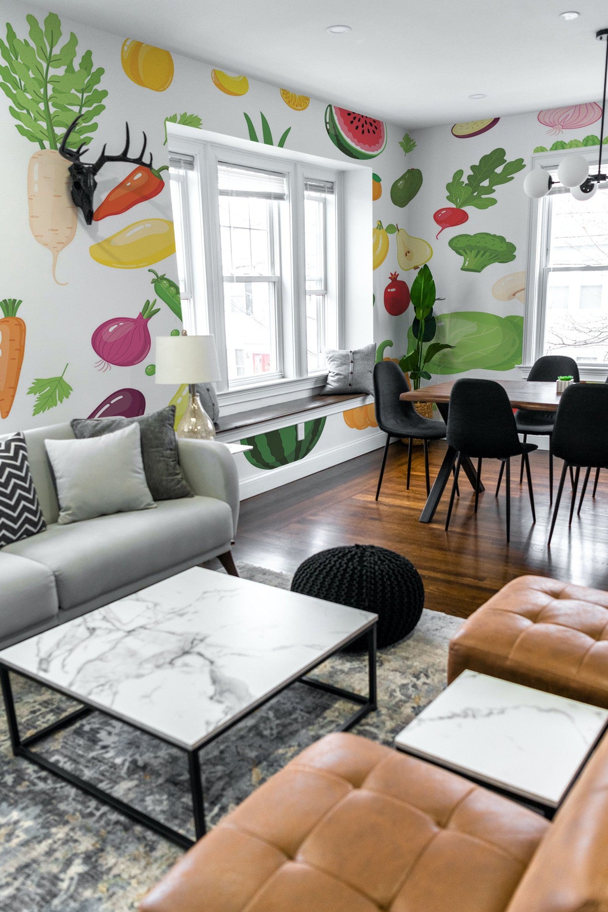 A modern living room interior with a vibrant wall mural featuring oversized fruits and vegetables.