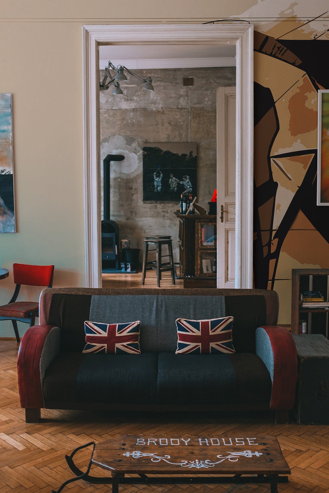 A modern living room interior with a wall mural, red sofa with cushions featuring the British flag, and decorative elements