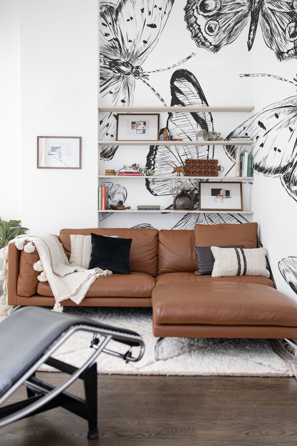 Cozy living room with a large black and white floral wall mural behind a brown leather couch