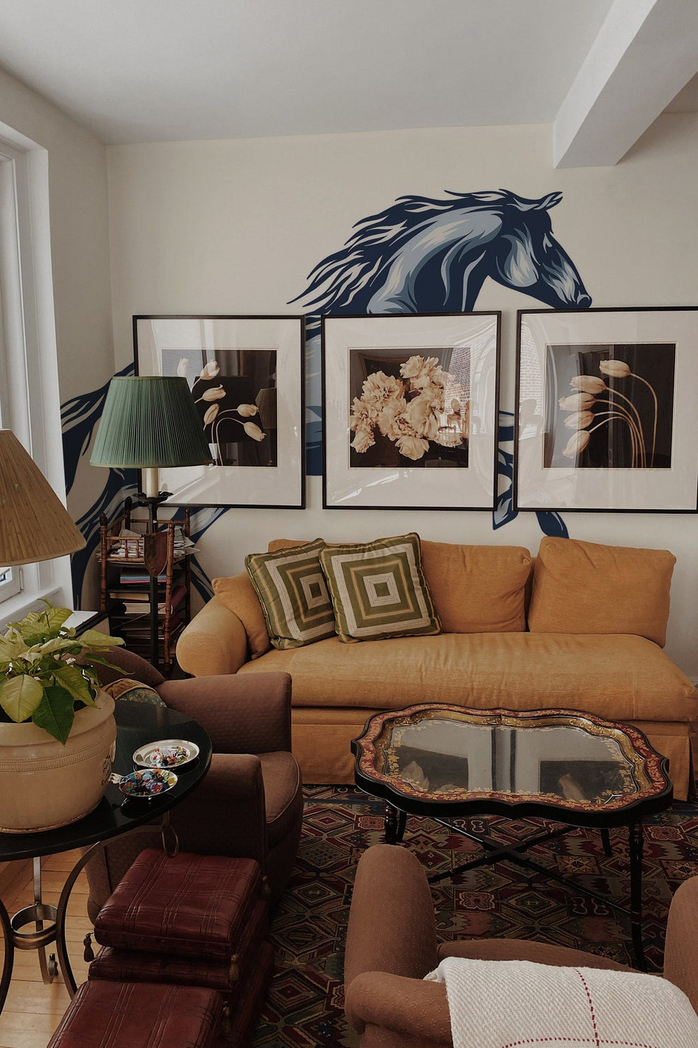 Interior of a living room featuring a large horse wall mural above the sofa and various framed pictures on the wall.