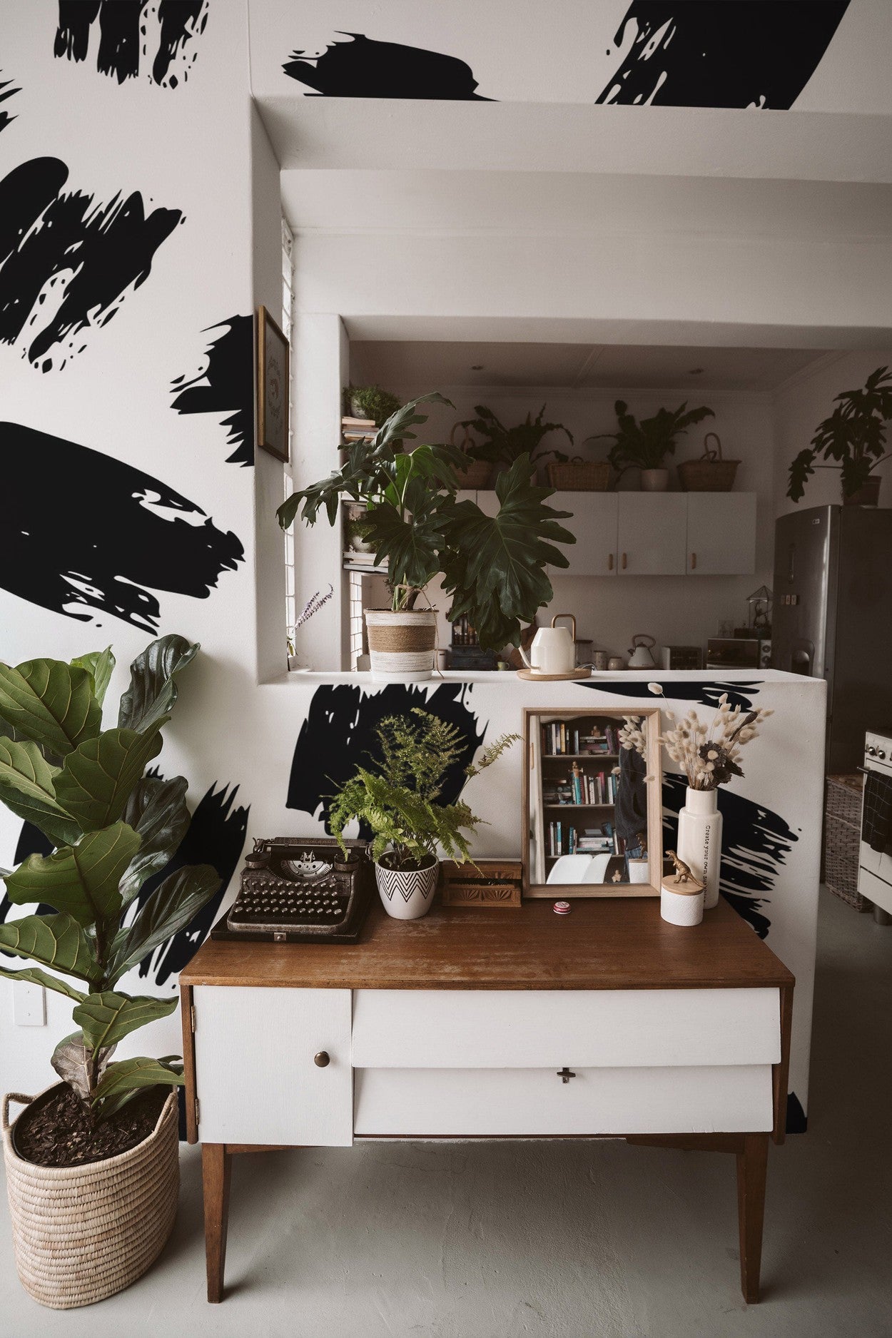 Cozy interior design with a desk, plants, and an abstract black and white wall mural