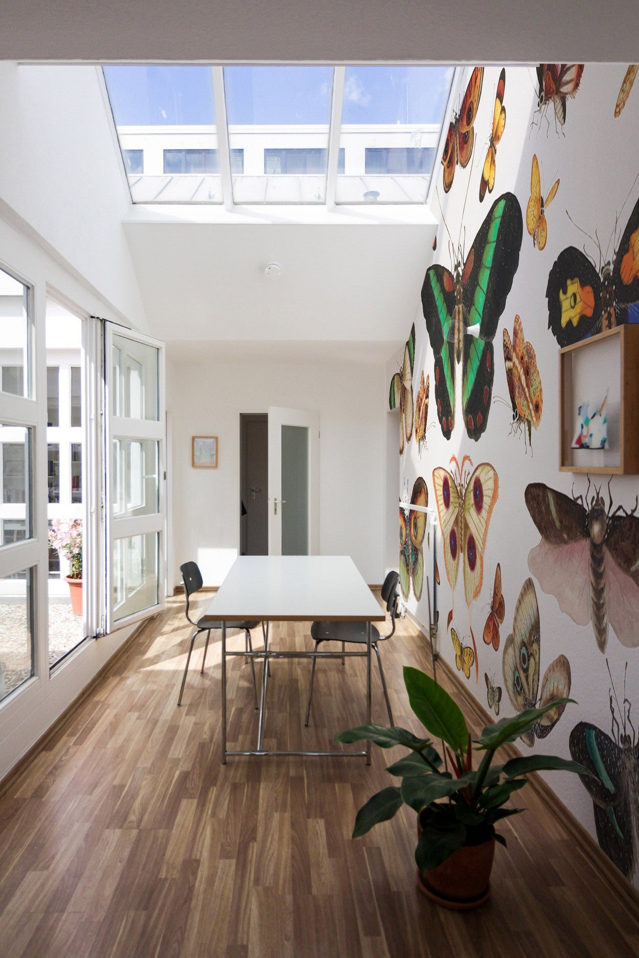 Bright room interior with large windows, skylight, and a wall mural featuring various butterflies
