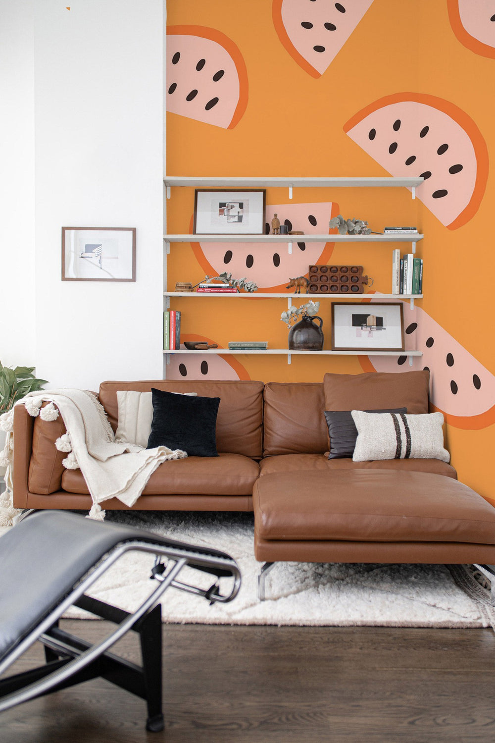 Contemporary living room interior with orange abstract wall mural, leather sofa, and shelving unit