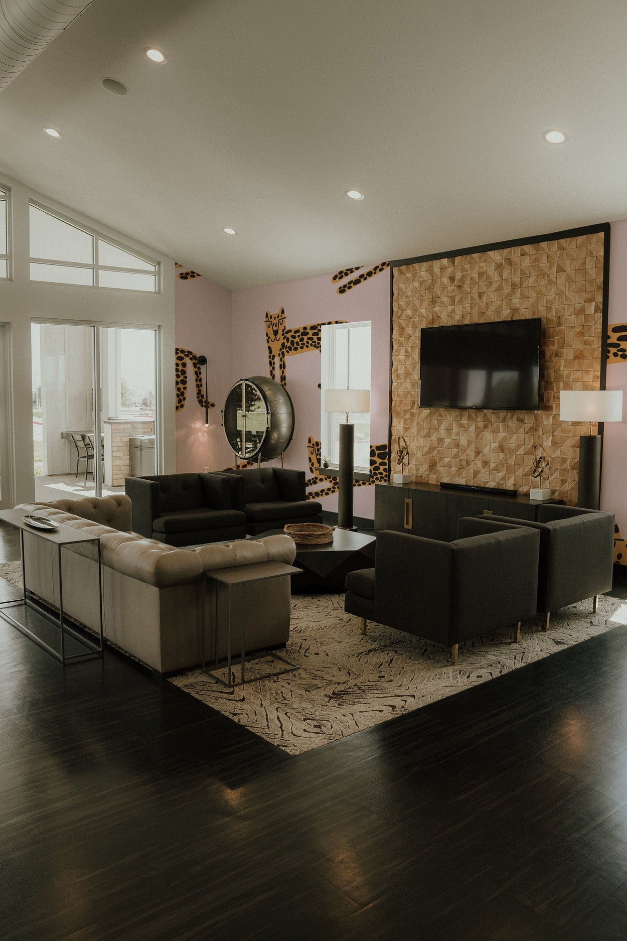 A stylish modern living room with dark hardwood floors and a large wall mural featuring animal print patterns.