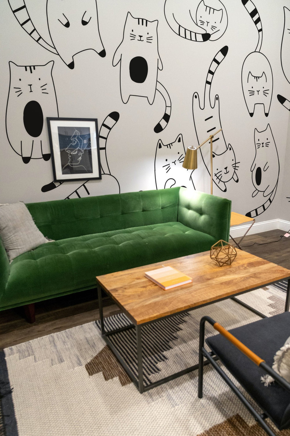 A contemporary living room with a green sofa, a wooden coffee table, and a whimsical cat-themed mural on the wall.