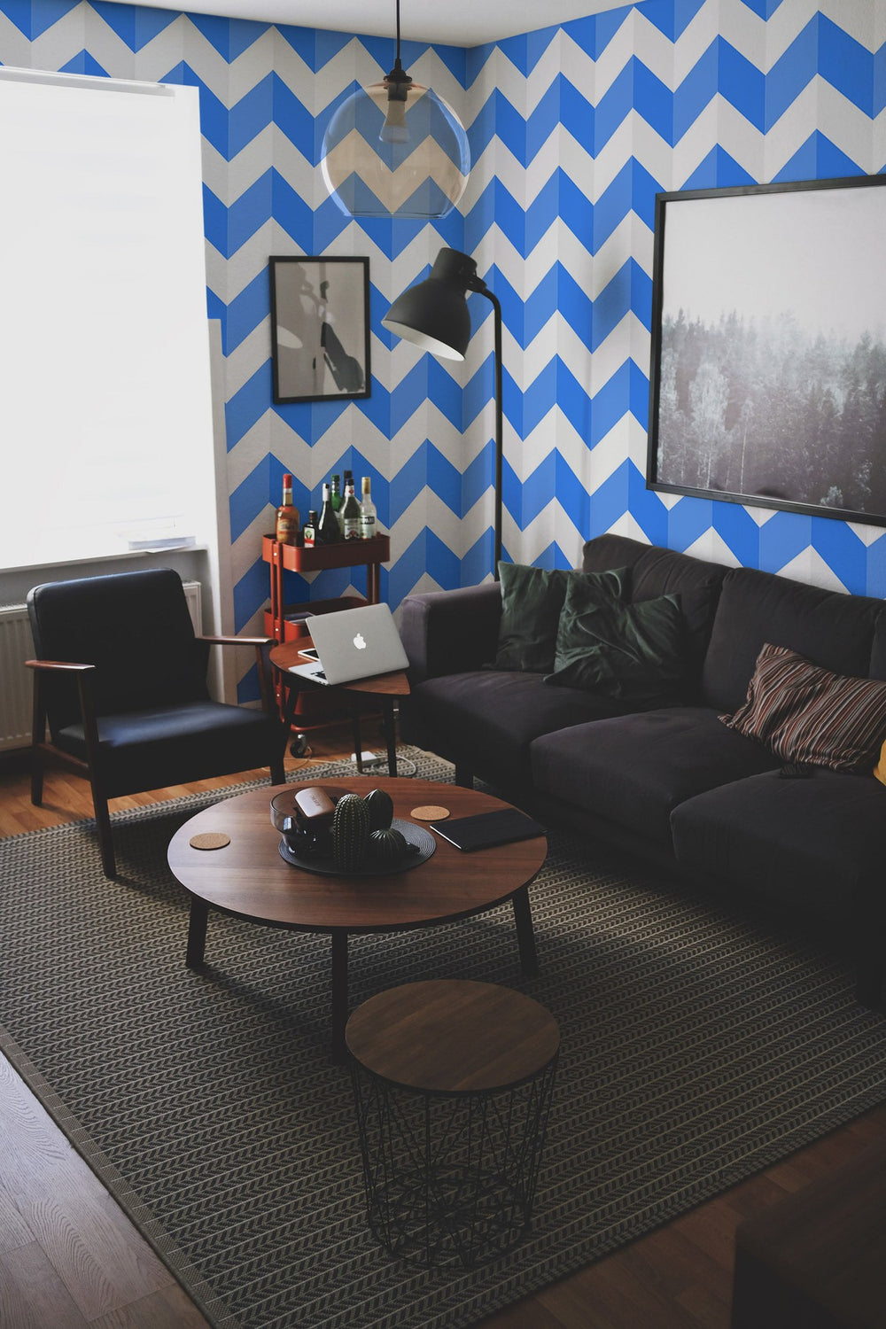 Interior of a modern living room with blue and white chevron pattern wall mural, stylish furniture, and framed artwork.