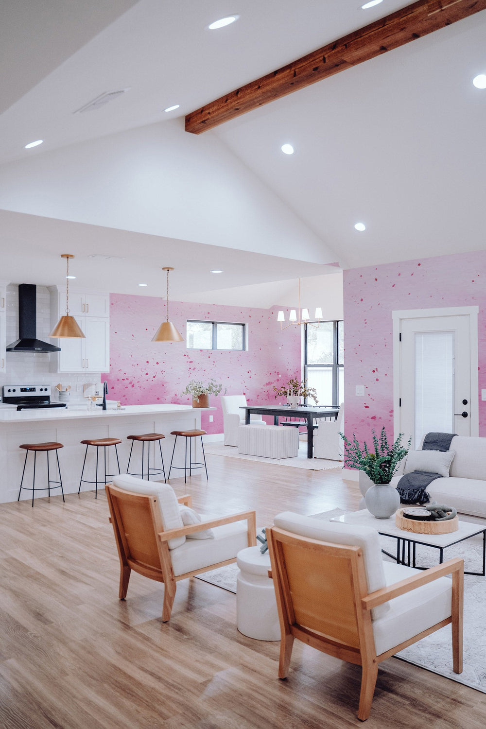 Interior of a modern living room with pink mural accent wall, wooden ceiling beams, and stylish furniture