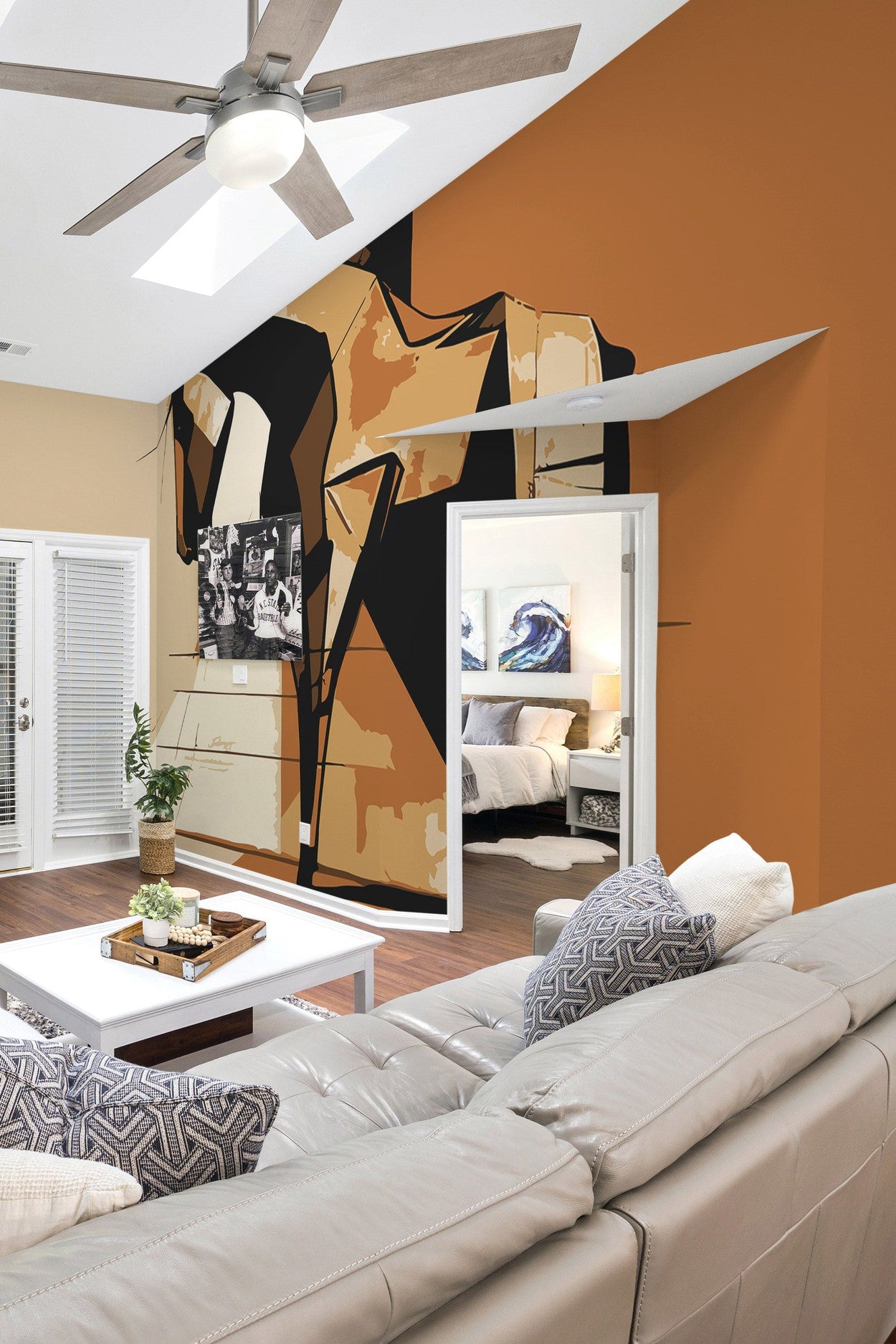 A contemporary living room featuring an oversized wall mural of a rhinoceros above a white sofa, with a warm orange wall and a ceiling fan.