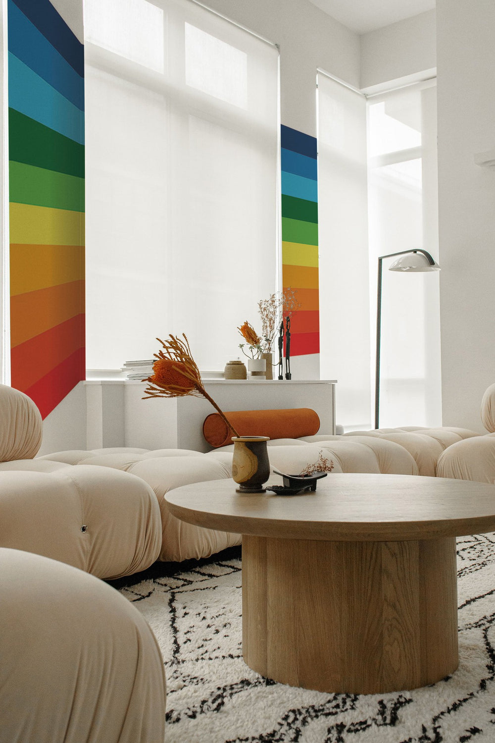 Modern living room with a bright rainbow striped mural on the wall, complemented by contemporary cream furniture and natural light.