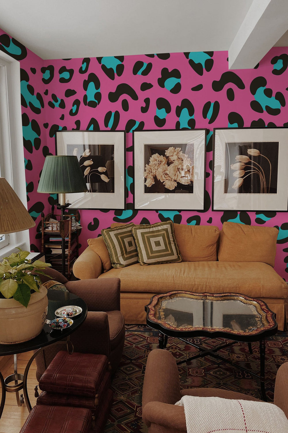 A cozy living room interior featuring a bold pink wall with black leopard print mural, adorned with framed art, and furnished with a warm-toned couch and comfortable chairs