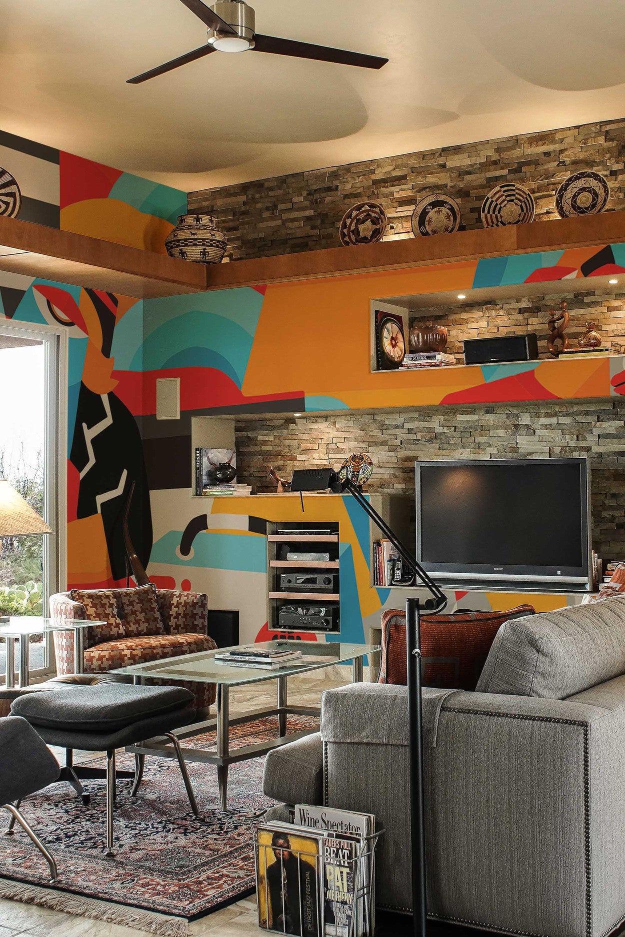 A living room interior featuring a colorful wall mural with abstract design, complemented by modern furniture and decorative ceiling fans.